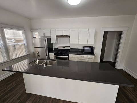 A kitchen with white cabinets and black countertops.