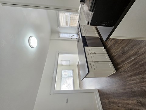 A white wall with a round light fixture and a mirror above a staircase.
