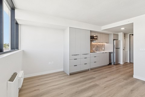 A kitchen with white cabinets and a wood floor.