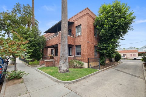 A red brick house with a tree in front.