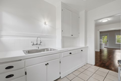 A white kitchen with a sink and cabinets.