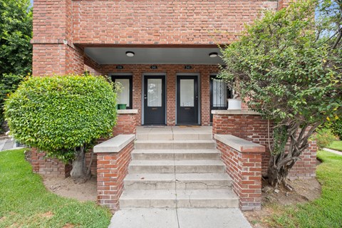 A red brick house with a black front door and steps leading to the entrance.