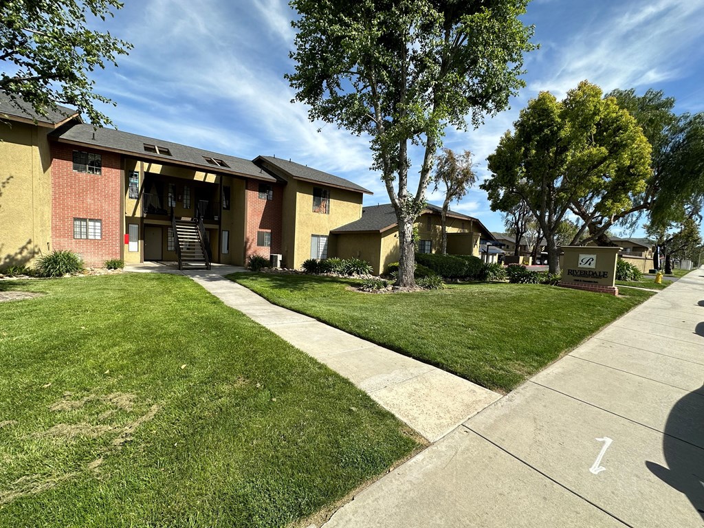 Sidewalk view of lawn and gardens at Riverdale Apartment Homes in Hemet, California.