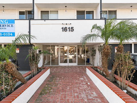 The image shows a building entrance with a sign that reads "1615" and a blue sign above it with the text "ING Service" and a phone number.