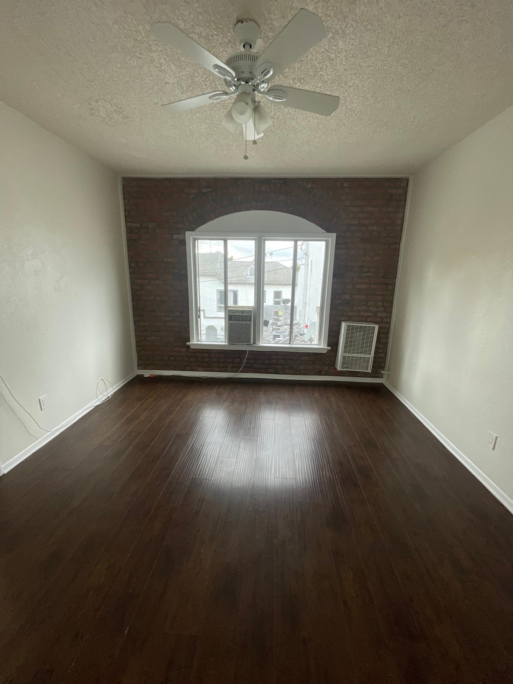 Bedroom with hardwood floor, ceiling fan, and air conditioning/heat at Sanborn/Hoover Apartments in Los Angeles, CA.