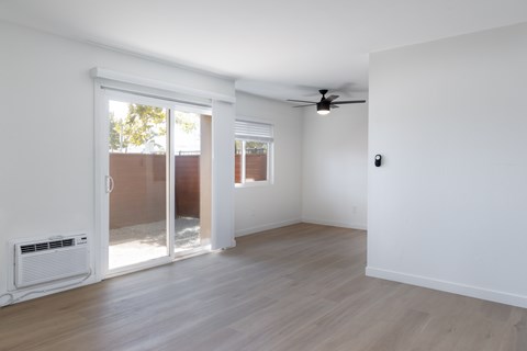A room with a sliding glass door and a ceiling fan.