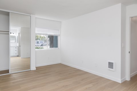 A room with a white wall and a window with blinds.