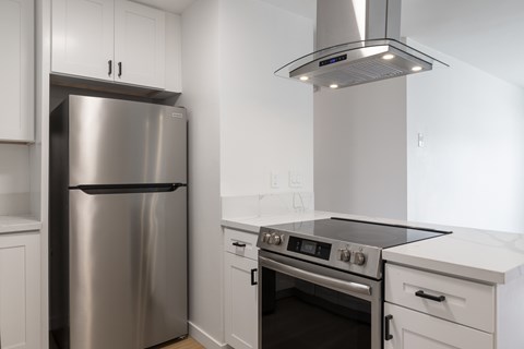 A modern kitchen with a stainless steel refrigerator and oven.