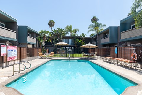 A swimming pool surrounded by a fence and chairs.