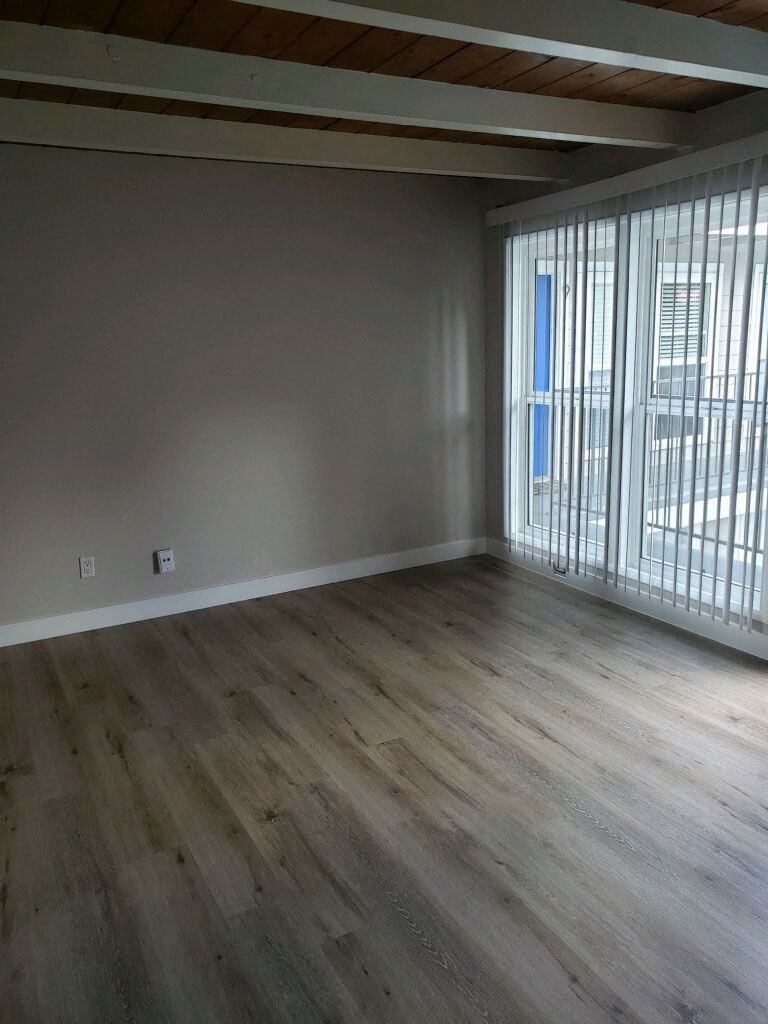 Living room with lots of natural light and open beam ceiling at 5747 Lauretta Street Apartments in San Diego, California.
