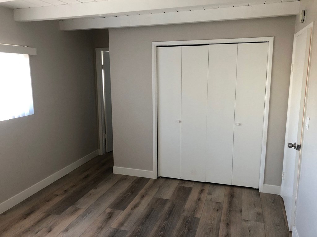 Bedroom with large closet and wood plank style vinyl flooring at 5747 Lauretta Street Apartments in San Diego, California.