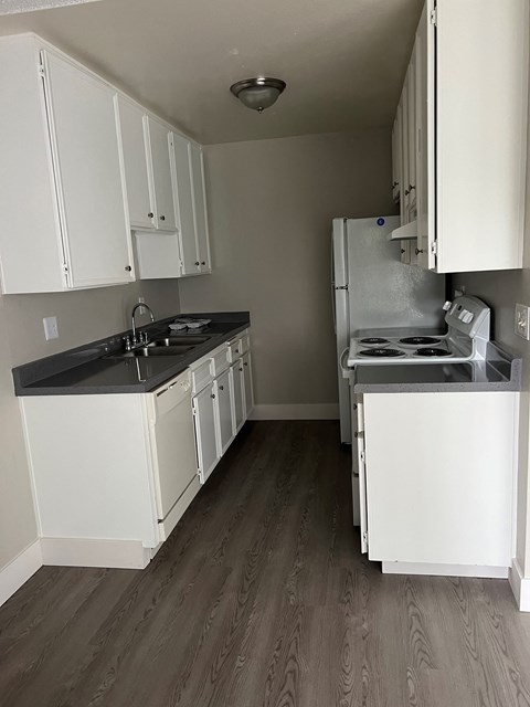 an empty kitchen with white cabinets and a stove and refrigerator