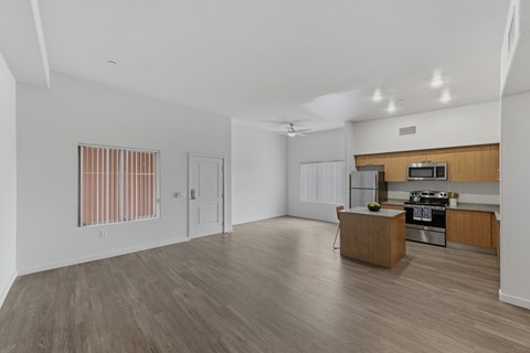 A spacious kitchen and living room with wooden floors and white walls.