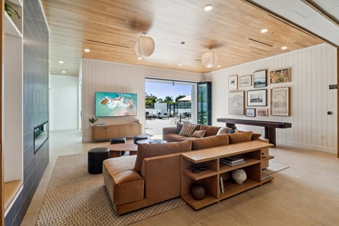 A living room with a brown couch and a painting of a beach scene on the wall.