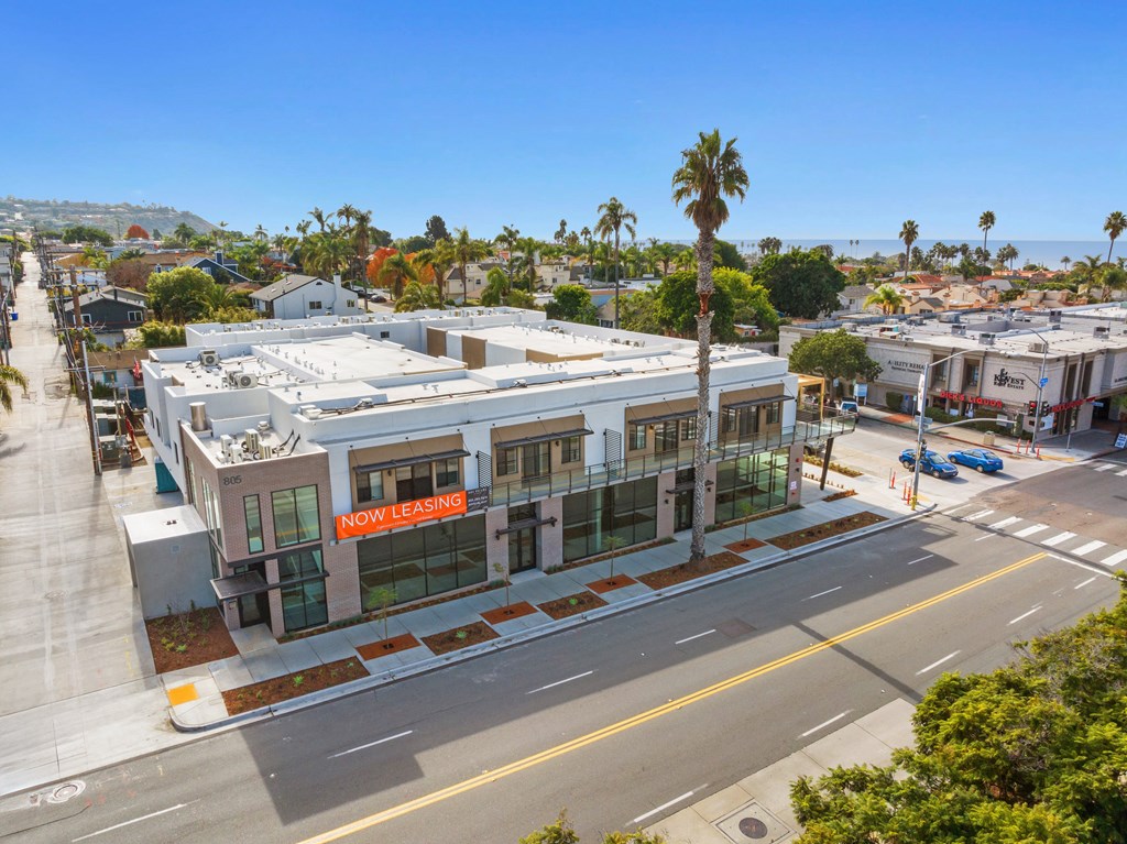 A street view of a building with a "Now Leasing" sign.