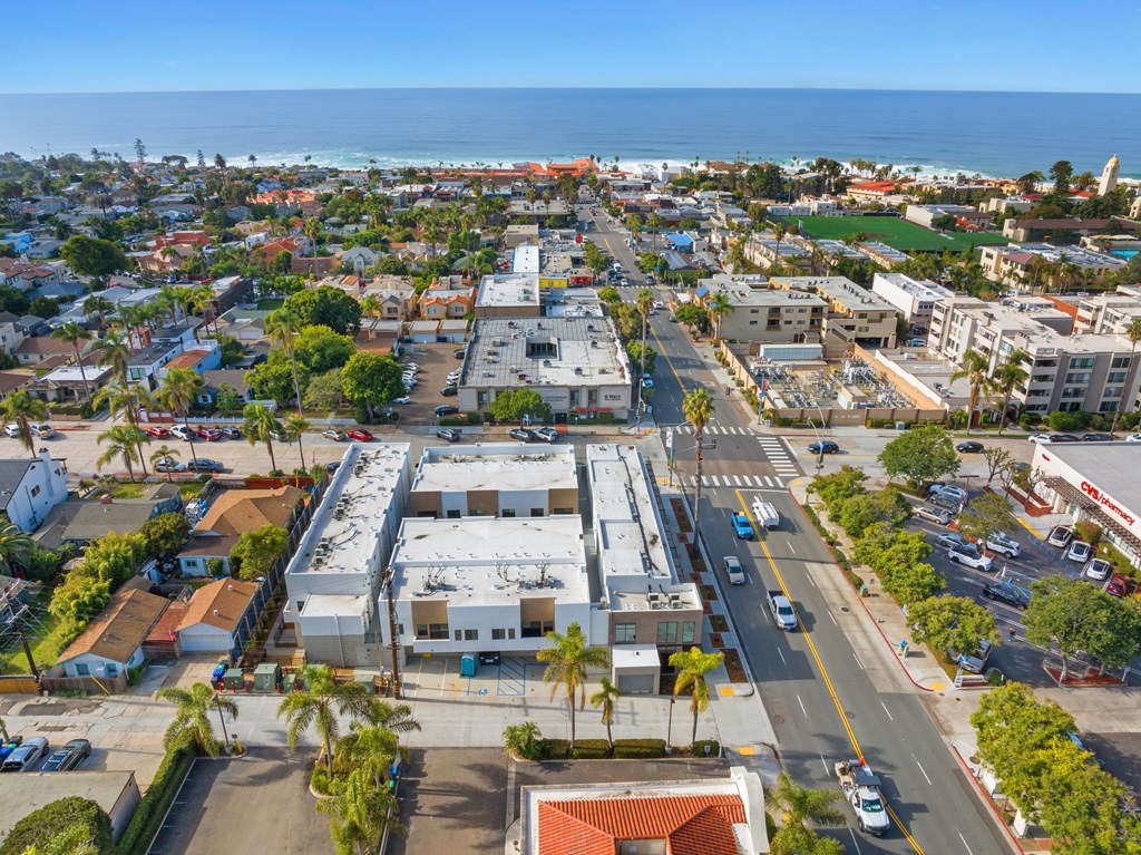 A view of a city with a large building in the center and cars on the road.