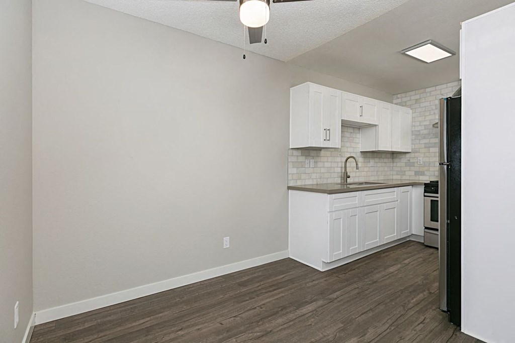 Dining area with ceiling fan next to kitchen with white cabinets at Solara Apartments.