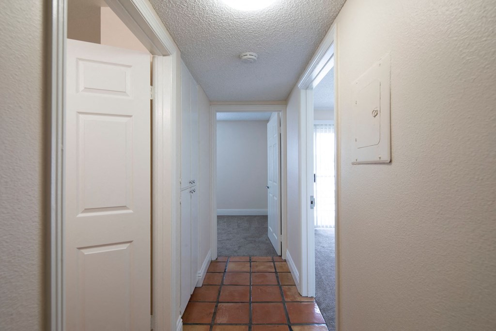Bedroom hallway with Saltillo tile flooring and closet space at the Atrium Apartments in San Diego, California.