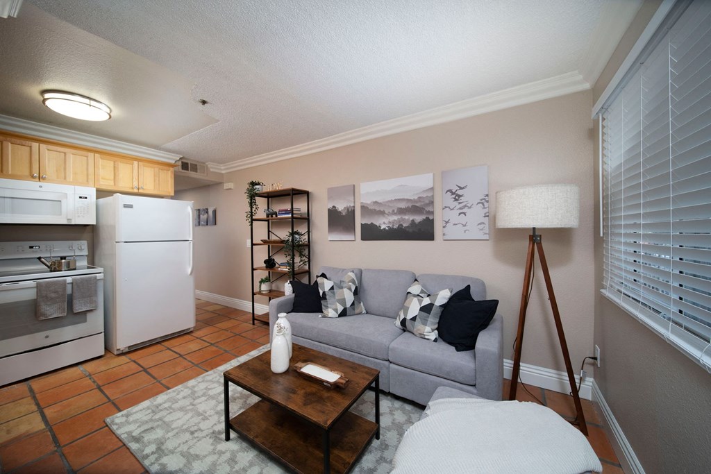 Living room with large window and open kitchen in model unit at the Atrium Apartments in San Diego, California.