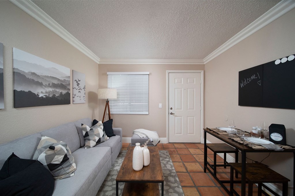 Living room with crown molding and Saltillo tile floors in model unit at the Atrium Apartments in San Diego, California.