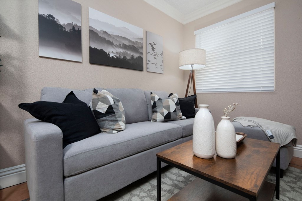 Living room of model unit with Saltillo tile flooring, crown molding and custom window blinds at the Atruim Apartments in San Diego, California.