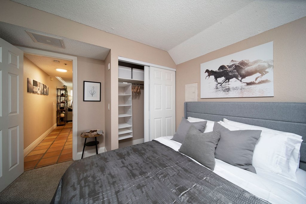 Bedroom in model unit showing spacious closets and berber carpet at the Atrium Apartments in San Diego, California.