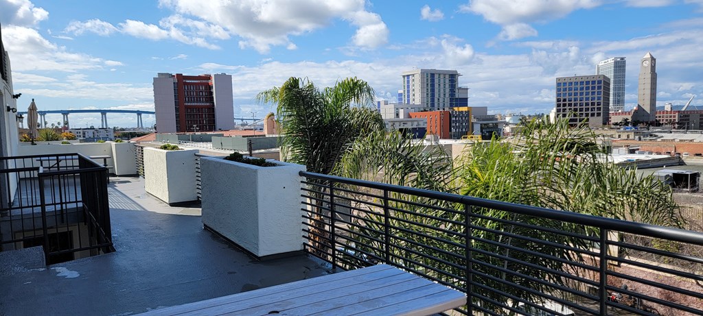 Patio tables, planters, and skyline view of San Diego at Atrium Apartments.