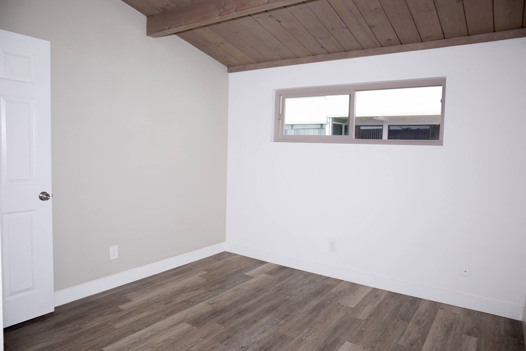 Bedroom with hardwood floor and exposed wood ceiling at Harbor Villa Apartments in San Diego, California.