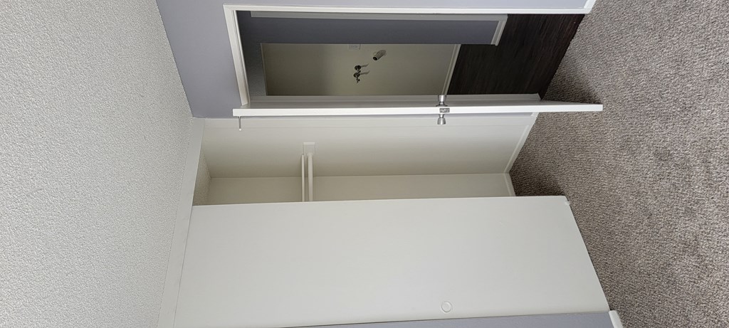 Carpeted bedroom and hallway nook with washer/dryer hookups at Grand Oaks Apartments in Lake Elsinore, California.