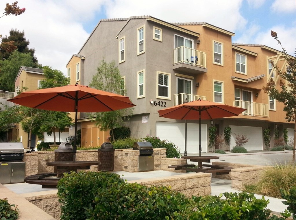 Picnic area with umbrella tables and gas barbeques at Serenata Townhomes in San Diego, California.