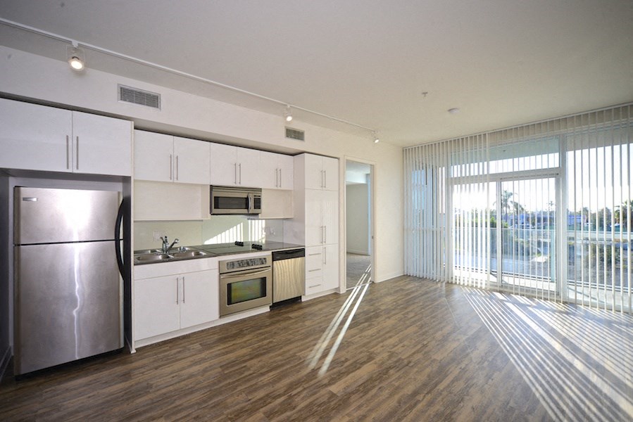 Large living room with hardwood floors, sliding doors to balcony and open kitchen at 12th Street Lofts in National City, California..