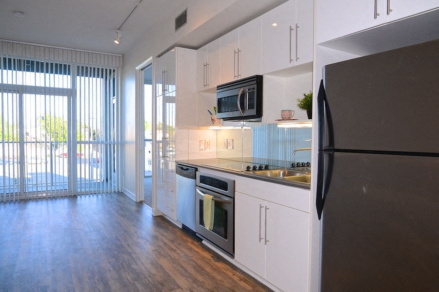 Kitchen with hardwood floors, stainless steel apliances and  patio access at 12th Street Lofts in National City, California.