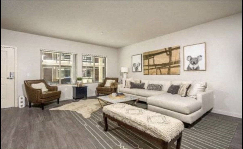 Living room with plank style flooring and lots of natural light from double windows at City Plaza Apartments in Escondido, California.