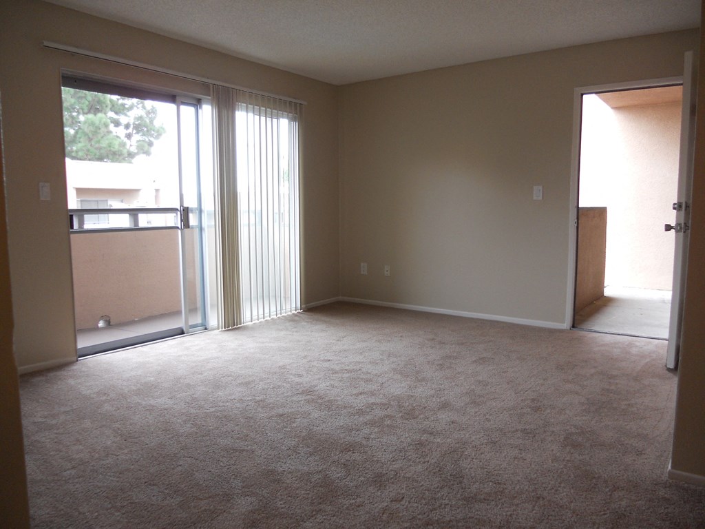 Carpeted living room with slidig glass door to private patio at Villa Pacific Apartments in Oceanside, California.