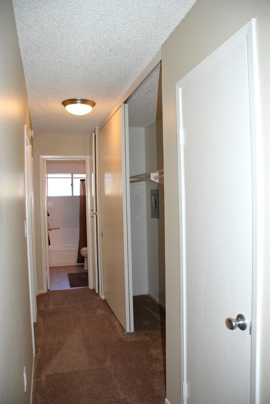 Carpeted bedroom hallway with closets and bathroom at Villa Pacific Apartments in Oceanside, California.