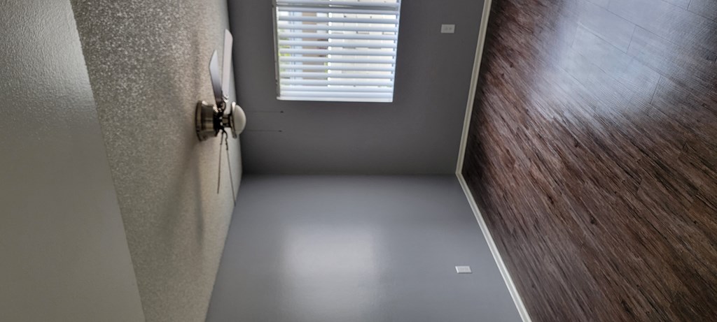 Living room with hardwood floor, ceiling fan, and lots of natural light at Grand Oaks Apartments in Lake Elsinore, California.