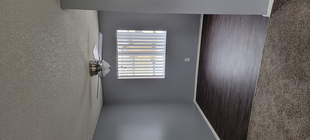 Dining room with hardwood floor, large window, and ceiling fan at Grand Oaks Apartments in Lake Elsinore, California.