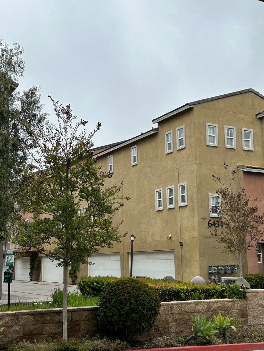 Attached two-car garages and gas barbeques amongst garden landscape at Serenata Townhomes in San Diego, California.