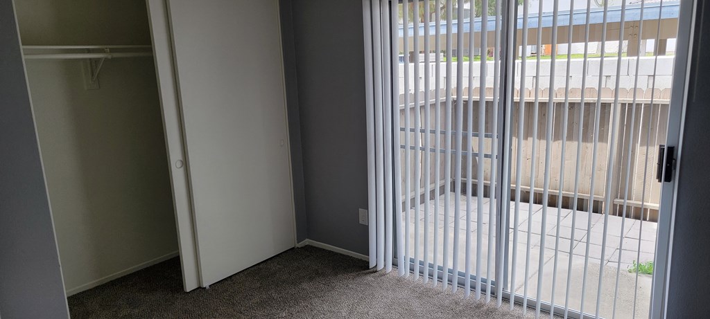 Carpeted bedroom with private porch at Grand Oaks Apartments in Lake Elsinore, California.