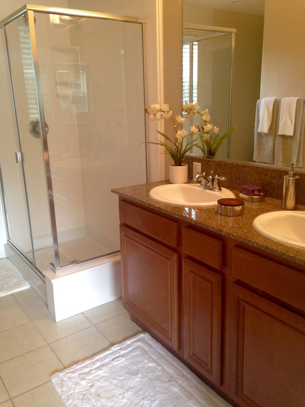 Bathroom with double vanity, tile flooring and walk-in shower at Serenata Townhomes in San Diego, California.