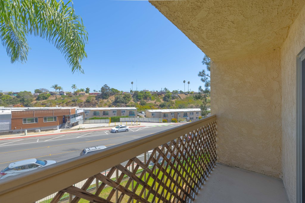 A balcony view of a building with cars on the street.