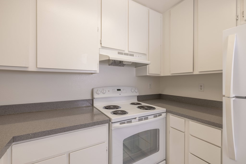 A white stove and oven in a kitchen with white cabinets.