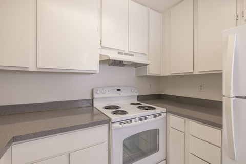 A white stove and oven in a kitchen with white cabinets.