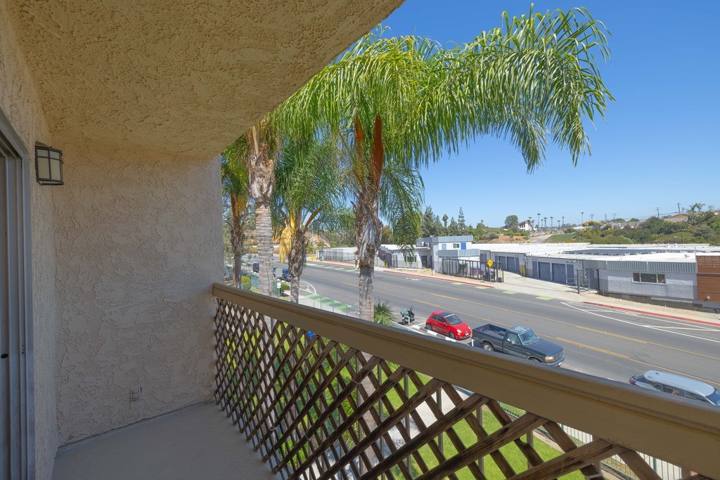 A balcony with a view of a street with cars and buildings.