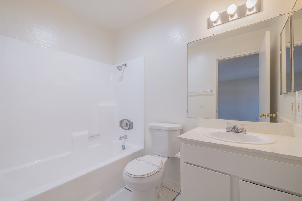 A white bathroom with a toilet, sink, and mirror.