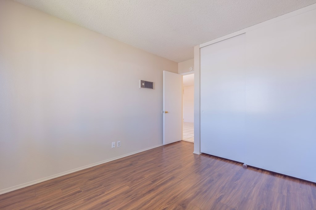 A room with a white door and wooden floor.