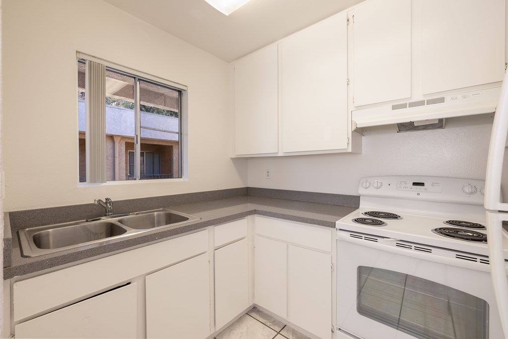 A kitchen with white cabinets and a stove top oven.