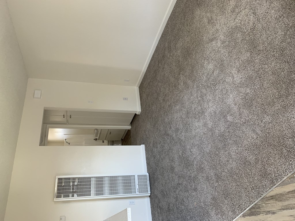 Carpeted living room in apartment at Carlsbad Sunset Senior Apartments in Carlsbad, California.