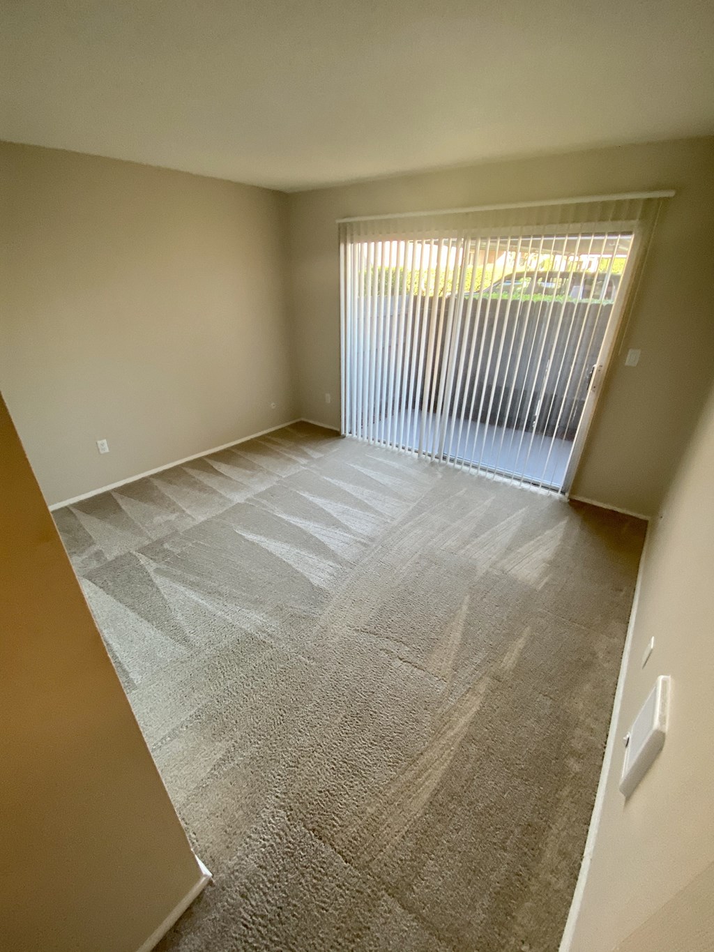 Carpeted bedroom with sliding glass door access to private porch at Villa Pacific Apartments in Oceanside, California.