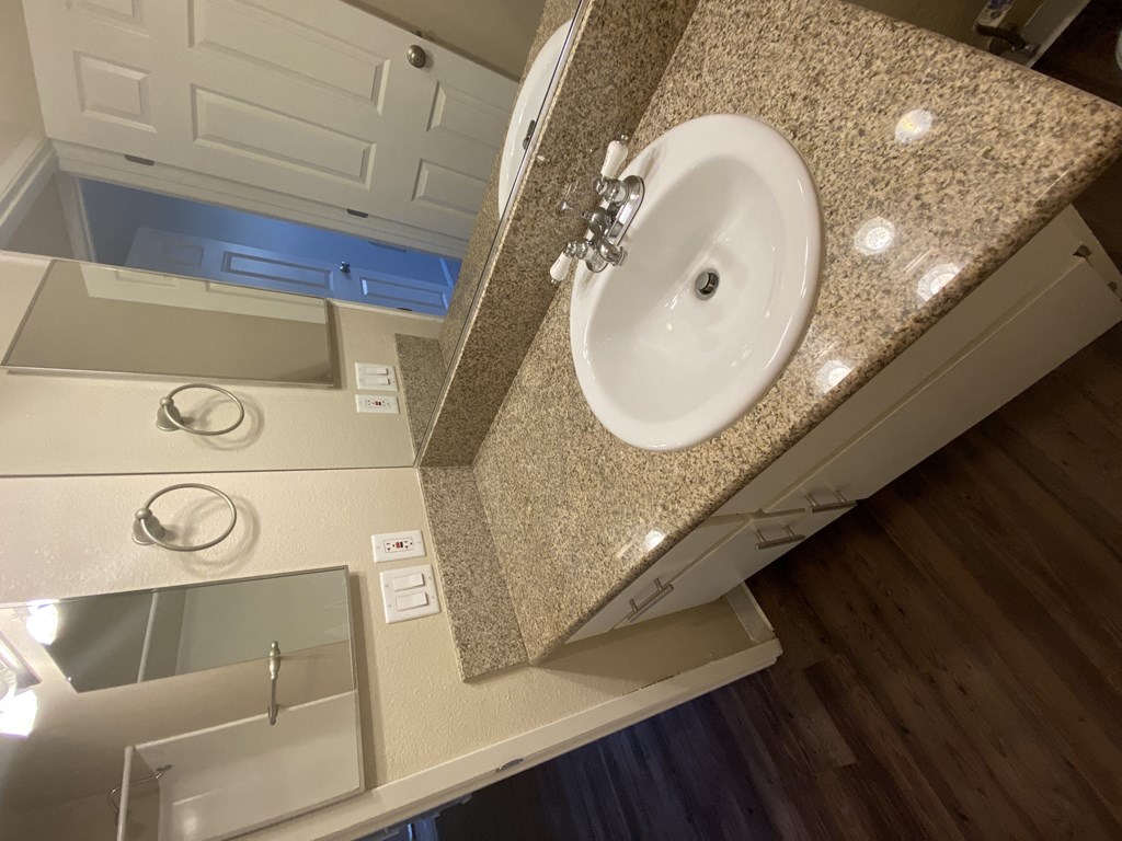 Bathroom with plank style flooring and vanity with white cabinets at Villa Pacific Apartments in Oceanside, California.